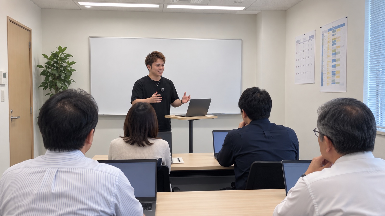 会議室で、講師が前に立って受講者に説明している研修の様子
